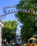 Entrance to Spirit of Halloweentown with stone pillars, trees, and a festive archway.