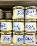 Jars of Oui by Yoplait yogurt in flavors like peach, key lime, and coconut on a store shelf.