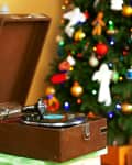 Vintage record player on a table with a decorated Christmas tree in the background.