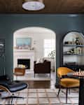 Blue sitting room or den with lots of curves, a vintage armchair, and a piano and chess table