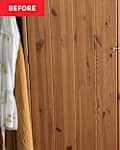 Wooden wardrobe with vertical planks, featuring a latch, and a white shirt and mustard-colored garment hanging nearby.