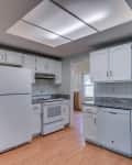 An empty white kitchen with wood floors and white tile backsplash