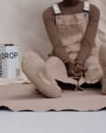 Person in beige overalls sitting with crossed legs, showing socks labeled "BACKDROP," next to a paint can.