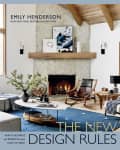 Living room with stone fireplace, wooden ceiling, blue rug, modern furniture, and abstract art on the mantel.