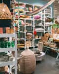 Home decor store with lights hanging and pillows in shelving and rattan chairs and woven baskets