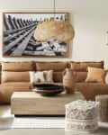 Living room with a brown sectional sofa, woven pendant light, wooden coffee table, and black-and-white framed artwork.