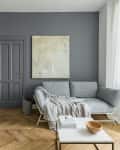 Gray living room with a gray sofa, abstract painting, wooden floor, and a white coffee table with a wooden bowl.