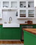 Kitchen with green lower cabinets, white upper cabinets, hexagonal tile backsplash, and a farmhouse sink.