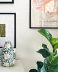 corner of room with book shelf, candle sticks, and art on wall, flower vase