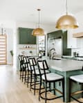 Kitchen with green and white cabinets and brushed brass pendant lights
