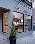Storefront of Hudson Grace featuring large windows, potted topiary, and modern decor visible inside.