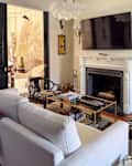 Living room with a light sofa, glass coffee table, fireplace, and decorative wall art.
