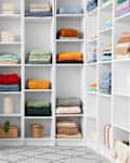 Walk-in closet with chest of drawers and shelves of folded clothing