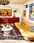 Bright living room featuring a striped sofa with decorative pillows, a yellow leather couch, a white coffee table, and a patterned rug.