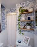 Small bathroom with blue and white toile wallpaper and small shower with white curtain