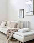 White sofa topped with decorative blanket in white, light filled living room.