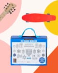 Aqua guitar, red skateboard, and Kid Made Modern Hanukkah craft kit on colorful geometric background.
