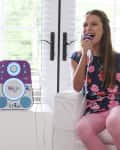 Two children singing into microphones with a purple karaoke machine between them.