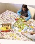 Two children playing the board game "Outfoxed!" on a floral tablecloth.