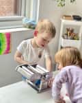 Kids using pasta maker to flatten play dough.