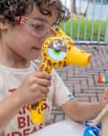 Child using Giraffe hammer to make a bird house.