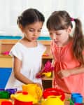 two kids playing together over colorful toys