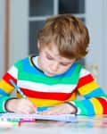 kid working on illustration with pens in front of him