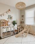Children's playroom with wooden slide, storage shelves, wicker baskets, and a bunny lamp on a patterned rug.