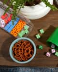 someone holding dice on top of a game with books and pretzels on a table
