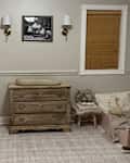 Nursery with a wooden dresser, changing pad, rocking horse, and a cozy reading nook with plush toys.