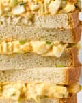 head on shot of four halves of an egg salad sandwich stacked on one another.