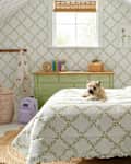 Cozy attic bedroom with green floral bedding, a small dog on the bed, and a light wood dresser.