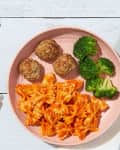 Pasta broccoli and meatballs for toddlers on a pink plate
