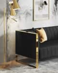 Black sofa with gold frame, marble wall art, gold floor lamp, and green plant in a modern living room.