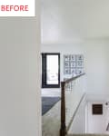 Hallway with vintage wall clock, staircase, and gallery wall of black-framed photos leading to a room with dark double doors.