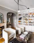 Living room with marble fireplace, white armchairs, built-in bookshelves, and a marble coffee table.