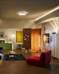 Modern living room featuring a blue sofa, red bean bag chair, green storage unit, and decorative artwork.