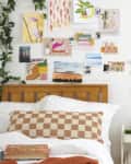 forward shot of bedroom with books on the bed, a desk with items on it and a wall filled with photos, jewelry organizer and a wall shelf