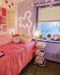 dorm room featuring Amazon Basics 3-Tier Rolling Utility or Kitchen Cart. Room has bed with pink bedding, speckled wallpaper wall with wavy neon, one lavender wall, windows. Cart is in front of a window