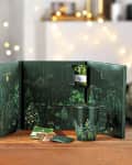 Palais des Thés advent calendar with festive tree design, tea packets, and matching mug on a wooden table.