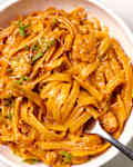 gochujang chicken alfredo pasta in a bowl with some twirled around a fork