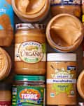overhead shot of peanut butter jars on top of each other with some jars opened showing the inside