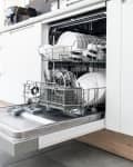 Open dishwasher with clean dishes and cutlery in a modern kitchen setting.