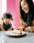 mom and toddler eating cake at dining table