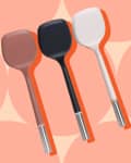 Three silicone spatulas in brown, black, and white with metal handles on a peach geometric background.