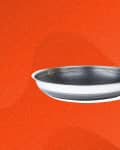 Stainless steel frying pan with a honeycomb pattern on an orange background.