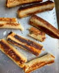 Toasted bread crusts on a baking sheet, sprinkled with sea salt.