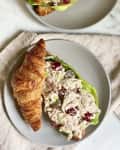 Croissant filled with chicken salad, grapes, and lettuce on a gray plate.