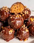 Chocolate covered peanut butter balls stacked with peanut crumble