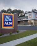 Aldi supermarket exterior with large logo sign, modern design, and landscaped entrance.
